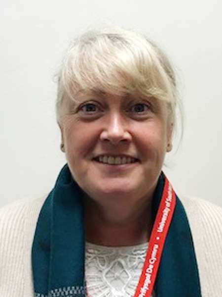 Michelle Romaniw, head of Chaplaincy Service at USW smiling to camera standing in front of a white background