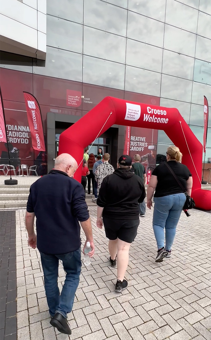 Guests being greeted under a large red archway that reads 