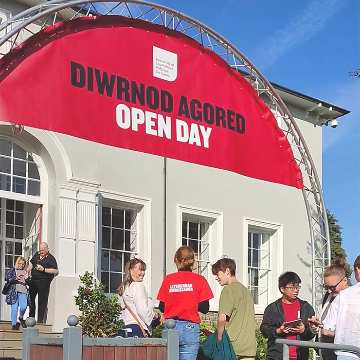 Guests being greeted under a large red archway that reads 