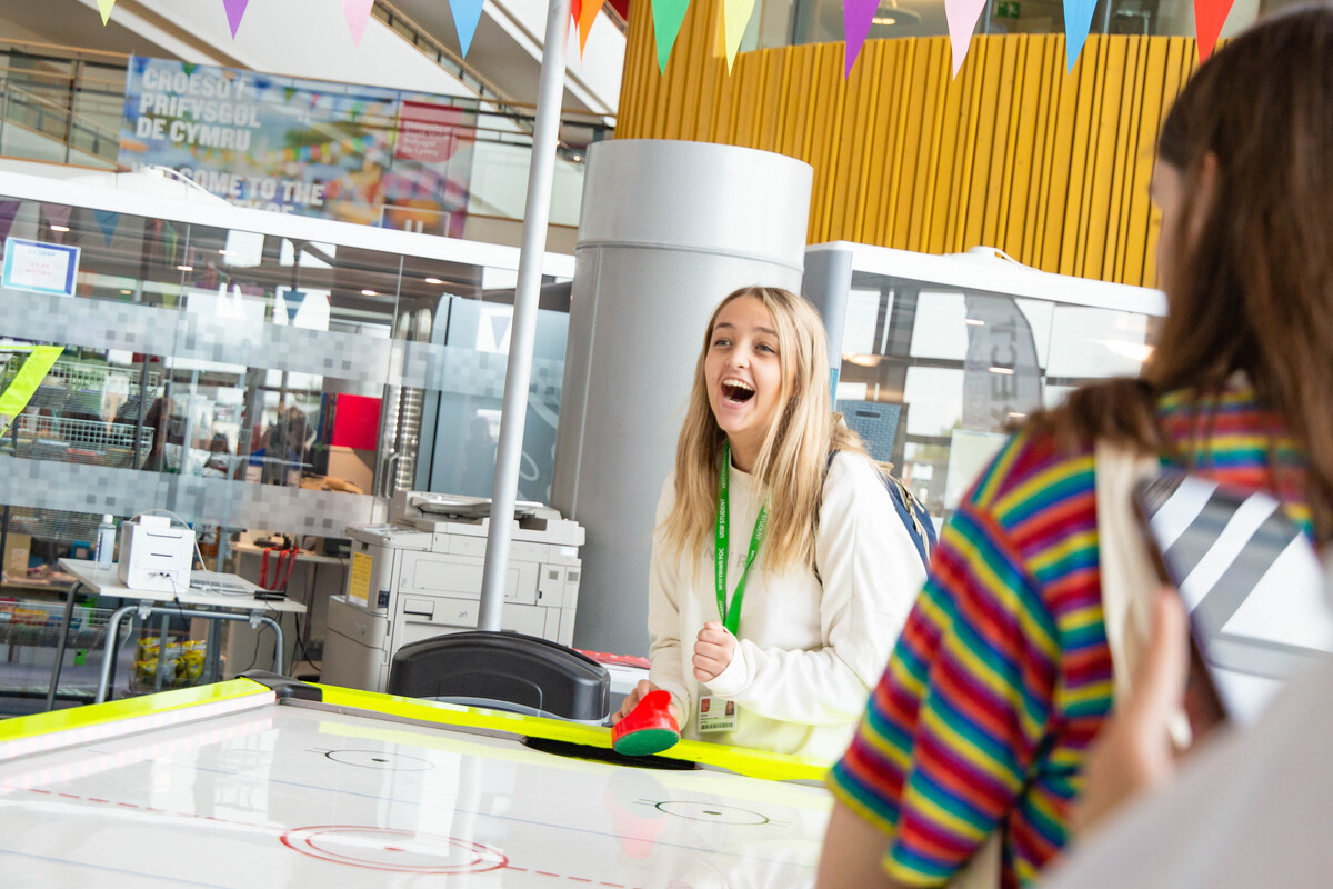 Two students playing air hockey and laughing