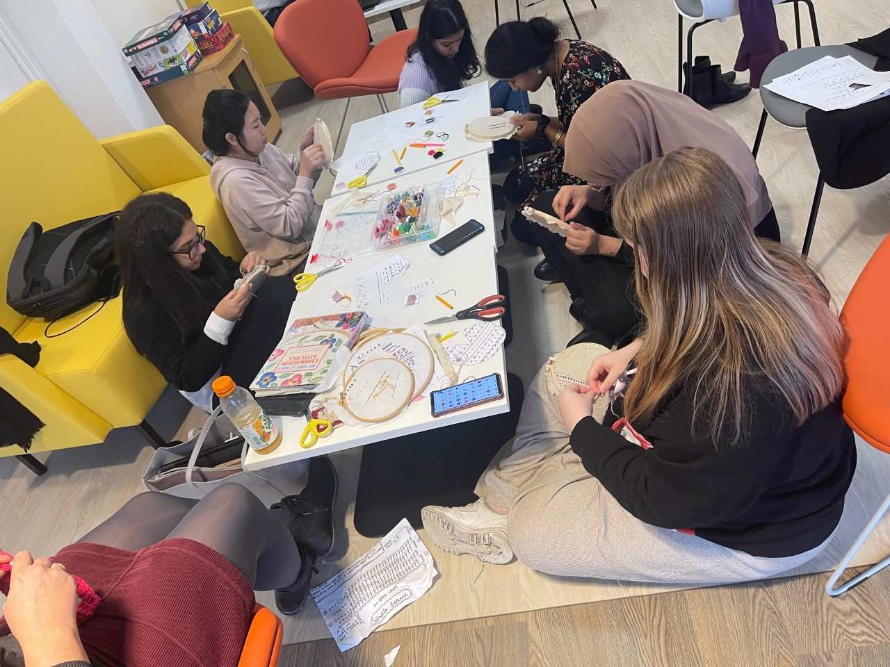 seven members of the resilife programme sat on the floor around a low table embroidering together.