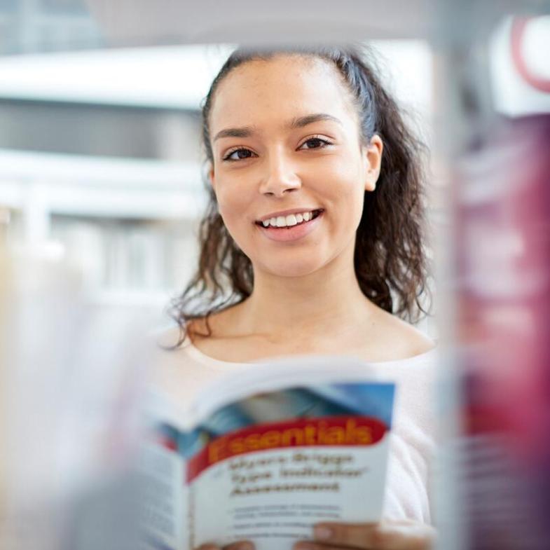 A student standing in the campus library smiling to camera