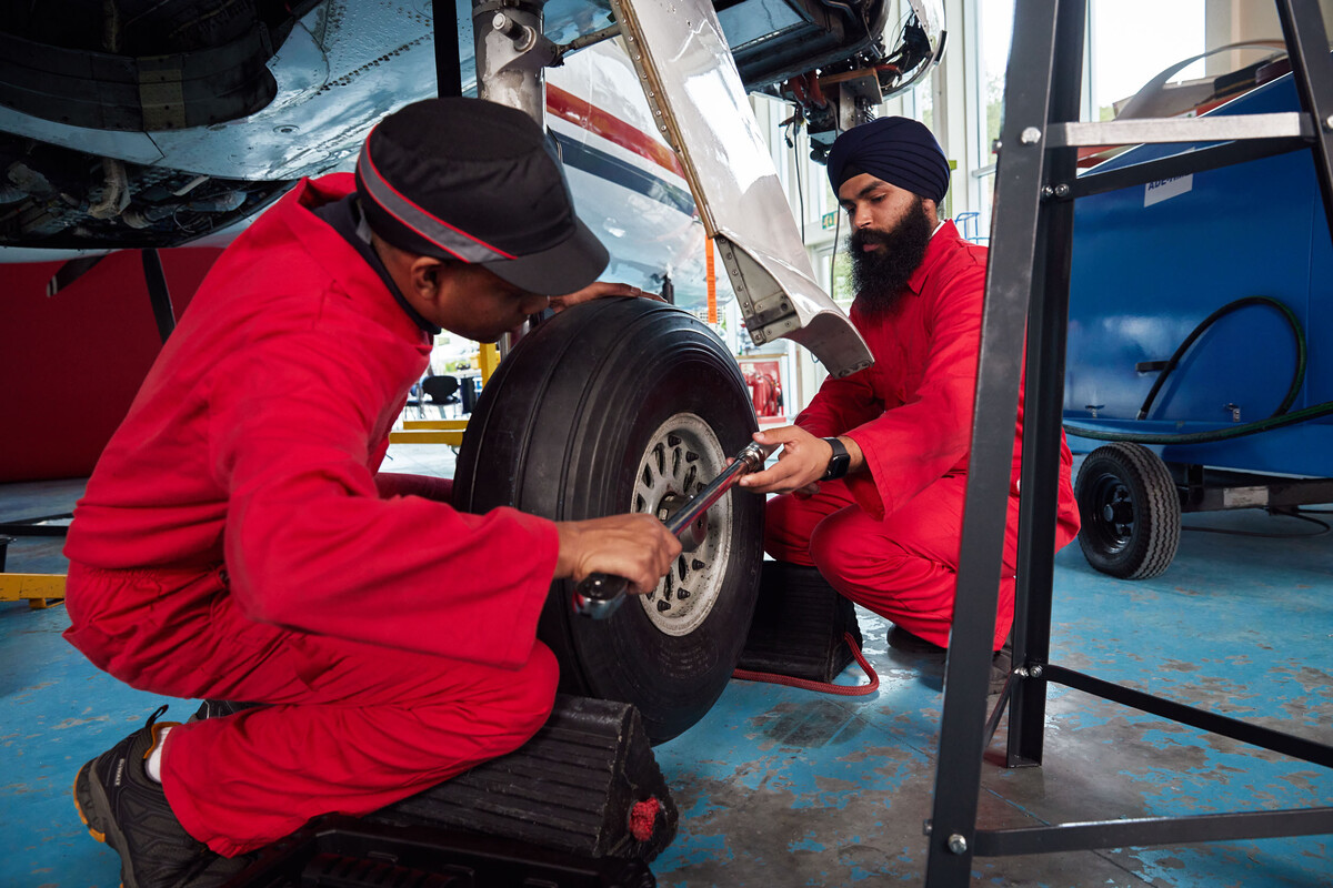 Two engineering students wearing red overalls working on the aircraft hangar in pontypridd campus