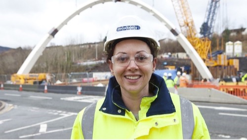 Close up image of Engineering student, Angharad, smiling at camera in front of construction project