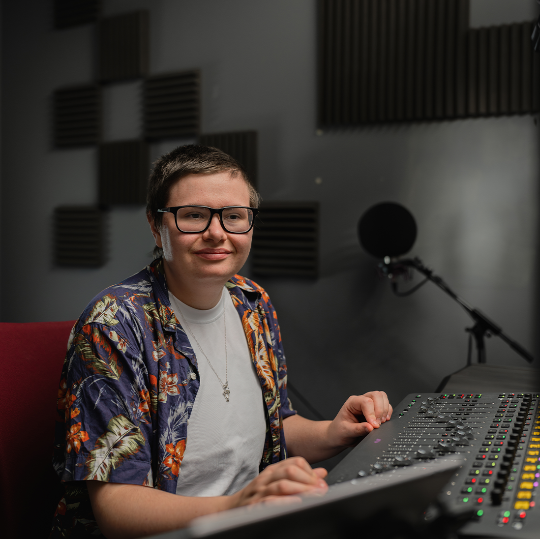 A film student sitting in a recording booth, using the equipment.