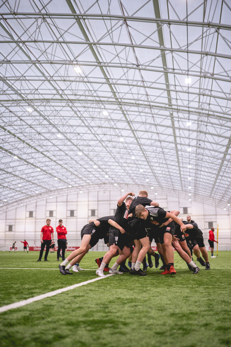 Group of rugby students taking part in a scrum during a training session