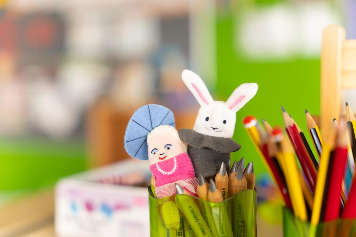Close up shot of a pencil pot with two finger puppets sat on top of the pencils