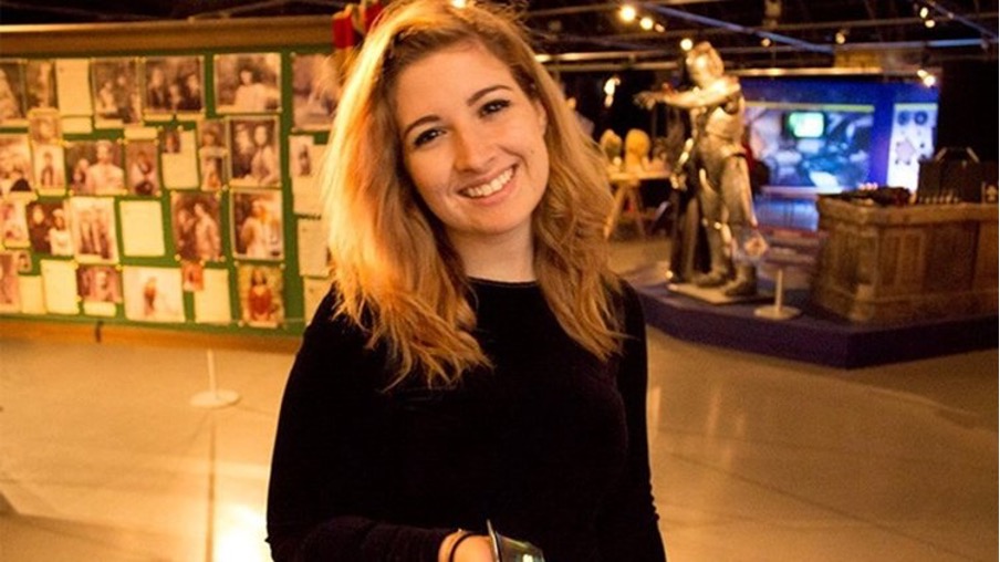 Charlotte smiles for a photo in front of an art exhibition
