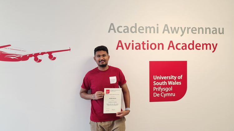 Shubh smiles at camera whilst produly holding a certificate