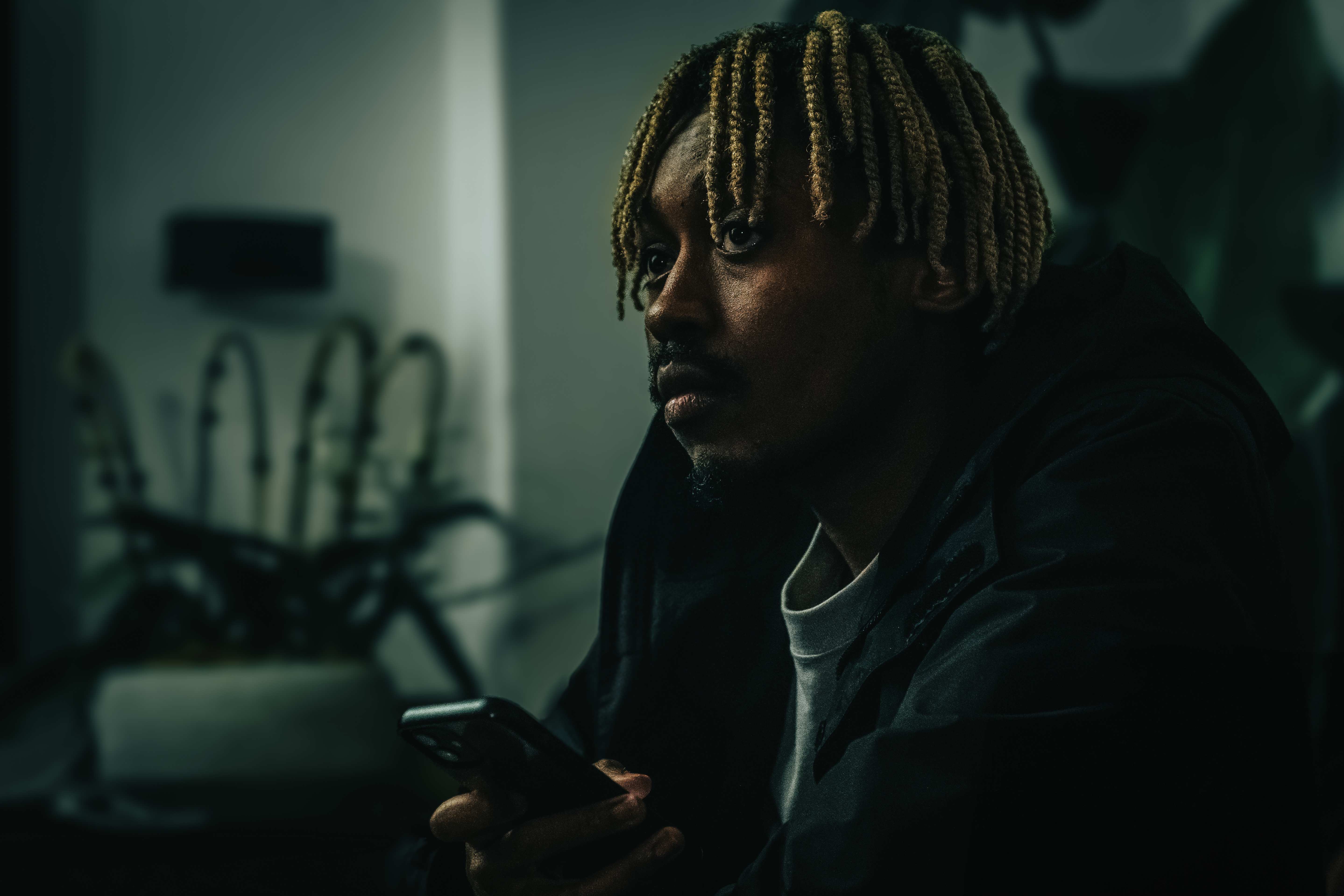 Student work - photograph of a student looking off past the camera holding a mobile phone