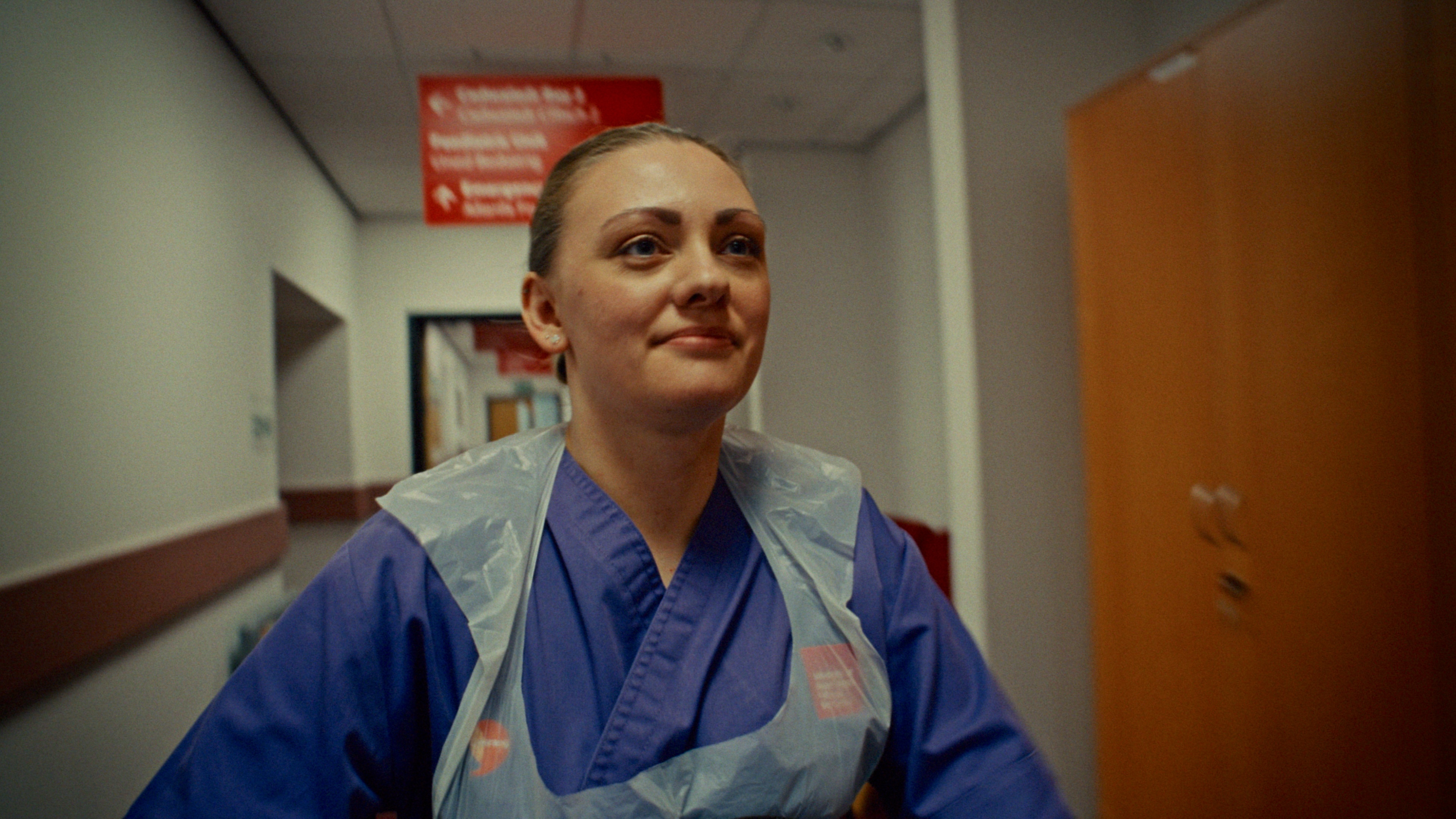 Close up shot of a nursing student wearing blue scrubs and an apron in the clinical simulation centre